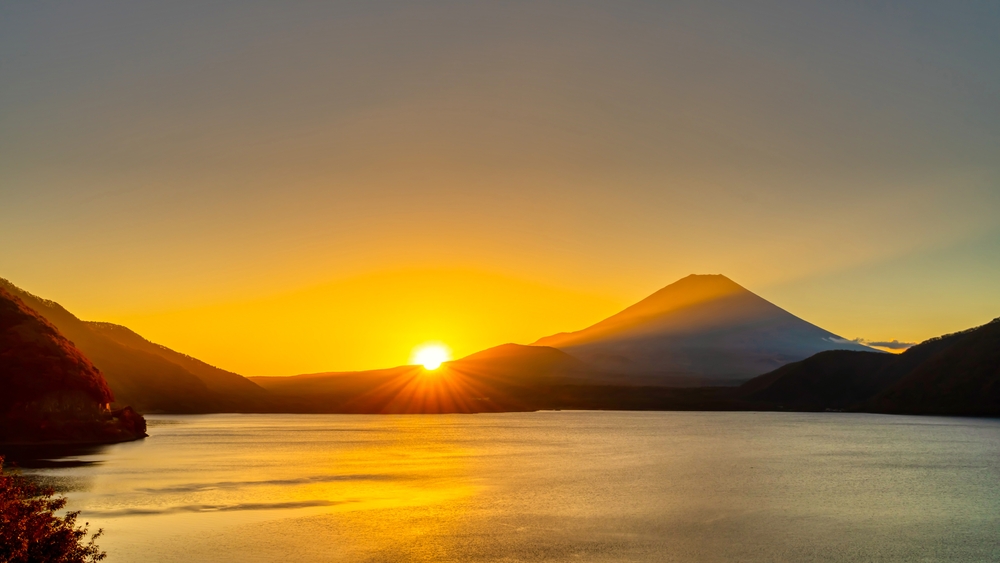 An image of a sunrise behind a mountain